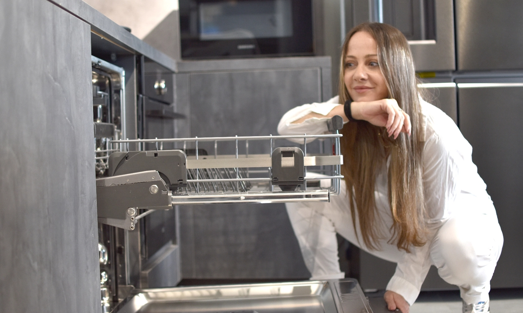 לקוחה מוציאה את סלסילת הכלים העליונה במדיח